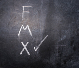 The letters F for women, M for men and X for the third gender are written in chalk on a black board, X is checked