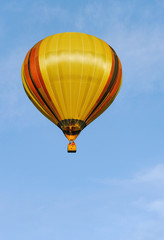 Colorful hot air balloon in the blue sky with clouds.