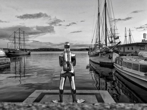 Statue at harbor against cloudy sky