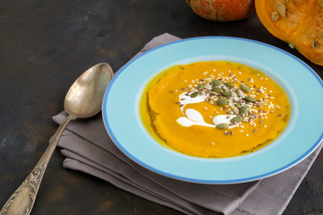 Vegetarian pumpkin cream soup on dark background.