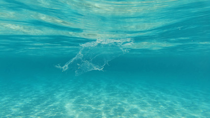 Fototapeta na wymiar Underwater photo of plastic bag floating in tropical exotic turquoise sandy beach