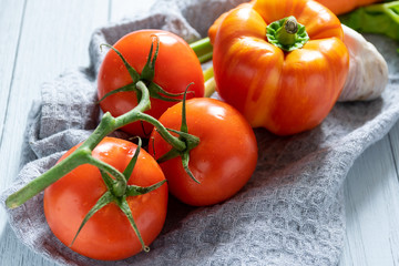 fresh vegetables on a light background. orange carrot, two-tone paprika, red tomato and salad on the kitchen table