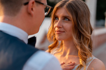Wedding couple looking at each other with love and happiness at park at sunset time.