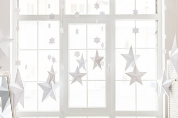 New year and Christmas concept, decorative paper stars hanging beside the window