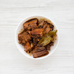 Homemade Filipino Adobo Pork on a white wooden table, top view. Flat lay, from above, overhead. Closeup.
