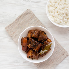 Homemade Filipino Adobo Pork with rice on a white wooden surface, top view. Flat lay, overhead, from above.
