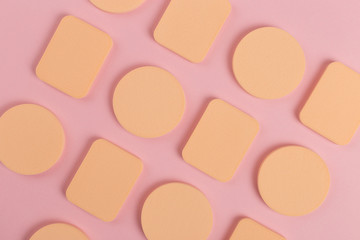 A lot of sponge, a beautiful blender for applying foundation or powder. Flat lay on a pink background, copy space.