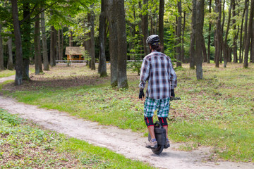 Person in protective wear rides a monowheel at the forest. Technology concept with copy space.