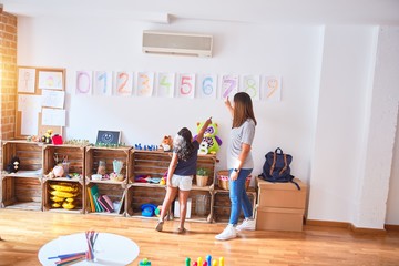 Beautiful teacher teaching maths to toddler girl playing at kindergarten
