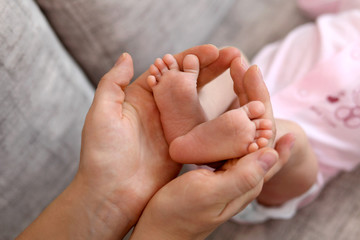 Obraz na płótnie Canvas little baby's legs in mother's hands
