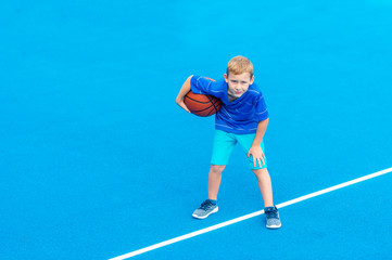 Adorable child playing the basketball in the basket field