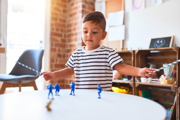 Beautiful toddler boy playing with figurine army soldiers at kindergarten