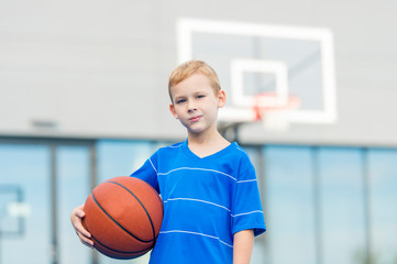 Adorable child playing the basketball in the basket field