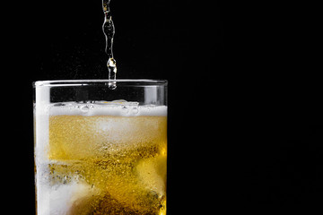 drink pouring in glass on a black background with copy space