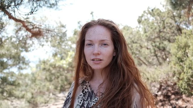 Portrait of red-haired woman in boho style outdoors. beautiful red-haired hippie girl. woman with green eyes and freckles relaxing at the beach in summer