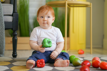 Fototapeta premium chubby child with red hair plays with vegetables