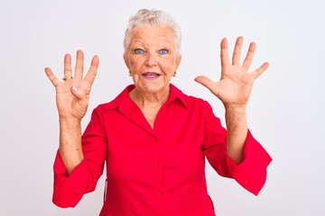 Senior grey-haired woman wearing red casual shirt standing over isolated white background showing...