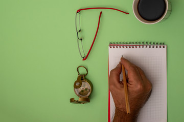 Green desktop, man drawing path for success, desktop with compass and red eyeglasses