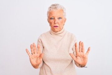 Senior grey-haired woman wearing turtleneck sweater standing over isolated white background Moving away hands palms showing refusal and denial with afraid and disgusting expression