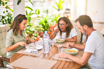 Beautiful family sitting on terrace eating foods speaking and smiling