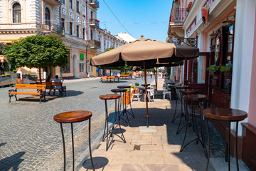 Outdoor cafe on the street. High tables and sunshade in summer cafe
