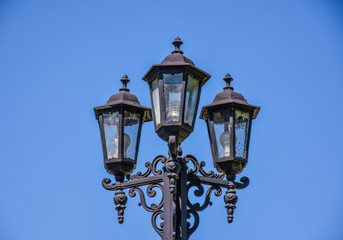 Fototapeta na wymiar Old street triple lamp. Old lamp with modern bulbs.