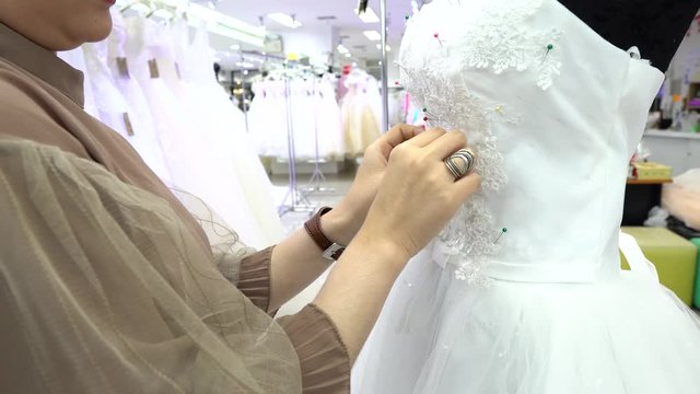Seamstress pins a wedding dress for alterations and design at a bridal boutique