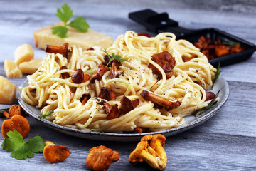 pasta with organic chanterelles. portion of spaghetti pasta with fried chanterelles in a creamy garlic sauce with cheese on a table