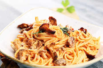 pasta with organic chanterelles. portion of spaghetti pasta with fried chanterelles in a creamy garlic sauce with cheese on a table