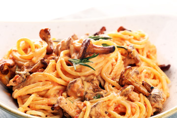 pasta with organic chanterelles. portion of spaghetti pasta with fried chanterelles in a creamy garlic sauce with cheese on a table