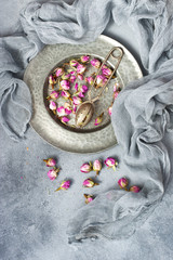 Metal sieve with dried  flowers of rose on gray background