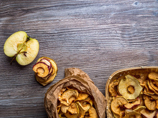 Homemade sun-dried organic apple slices, crispy apple chips, on wooden background and fresh apple. Copy space, top view