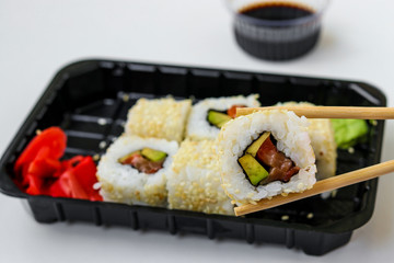 Syake rolls in a set of 6 pieces in a black box, with ginger, wasabi and soy sauce, fast food, horizontal orientation