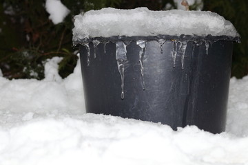 Winter atmospheric and motion picture with white snow, ice and mound of icicles on black container...