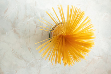 Yellow spaghetti in glass jar on marble kitchen table. Ingredient for Italian pasta. Raw food and cookware, close-up
