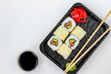 Syake rolls in a set of 6 pieces in a black box, with ginger, wasabi and soy sauce, fast food, horizontal orientation, top view