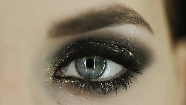Golg make up. Makro shot of beautiful eye of girl with golden shades. Girl opens her eye. Looks at the camera. Clear skin. 