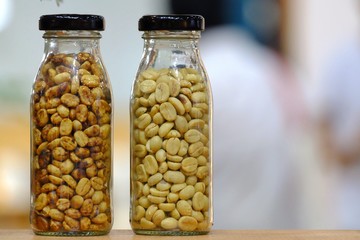 A pair bottle of raw coffee beans on the wooden table with indoor light