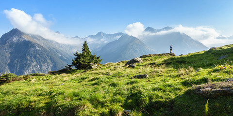 Wanderer in den Alpen mit wolkenverhangenen Bergen als Panorama im Hintergrund