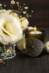 Fototapeta na wymiar Yellow lisianthus flowers and lit candle