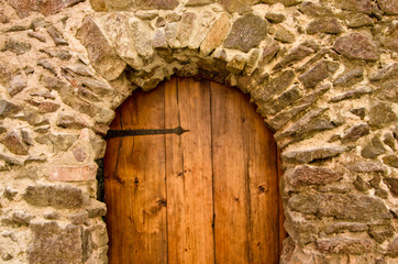 Fototapeta na wymiar An old, medieval wooden door in a wall of bricks