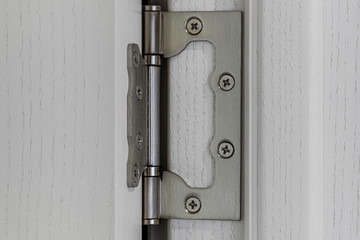 Closeup view of a hinge in white wooden doors.