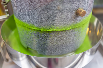 Matcha green tea grinding stone machine in motion with vibrant colorful powder in factory or tea...