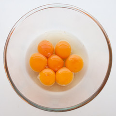 Seven eggs cracked in a glass bowl