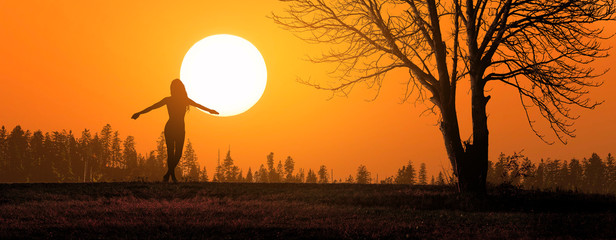 free and happy woman raises her arms at sunset
