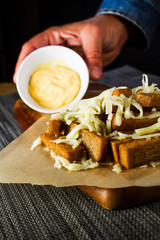 Appetizer of rye bread- croutons with cheese. Cheese sauce in a man's hand with rye bread croutons close-up.