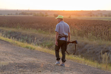 Hunting period, autumn season open. A hunter with a gun in his hands in hunting clothes in the autumn forest in search of a trophy. A man stands with weapons and hunting dogs tracking down the game.	