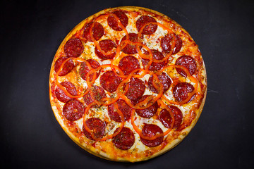 Pepperoni pizza close-up on a black background top view.