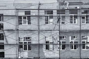 Workers paint and plaster the facade of the house, black and white photo.