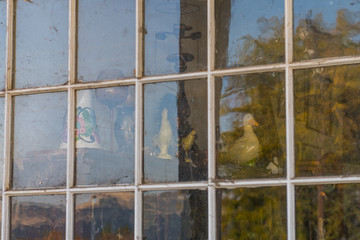 Old decorative objects behind the window of an abandoned gas station in Maryhill